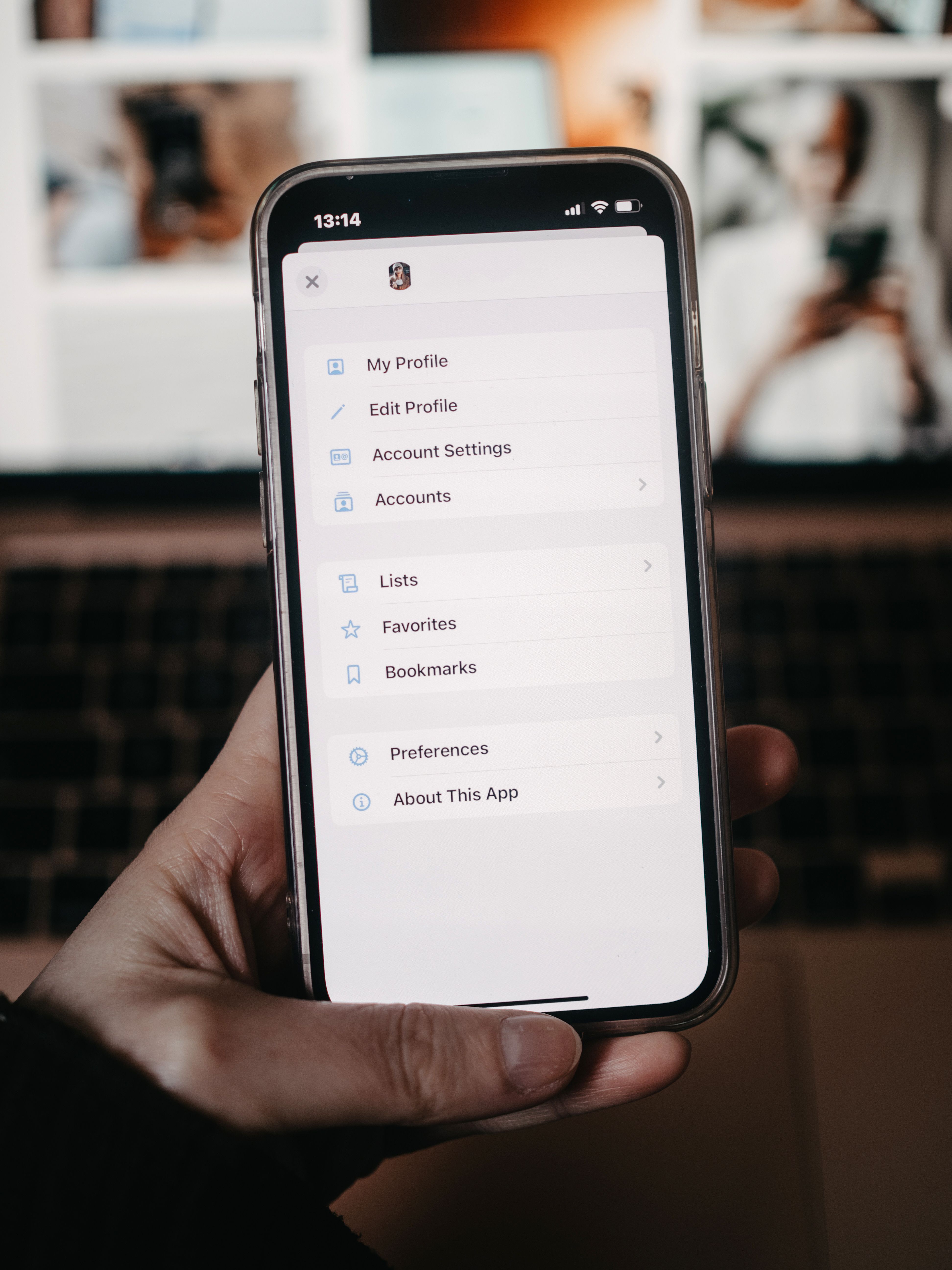 A person holds a smartphone showing the settings menu in front of a blurred background.