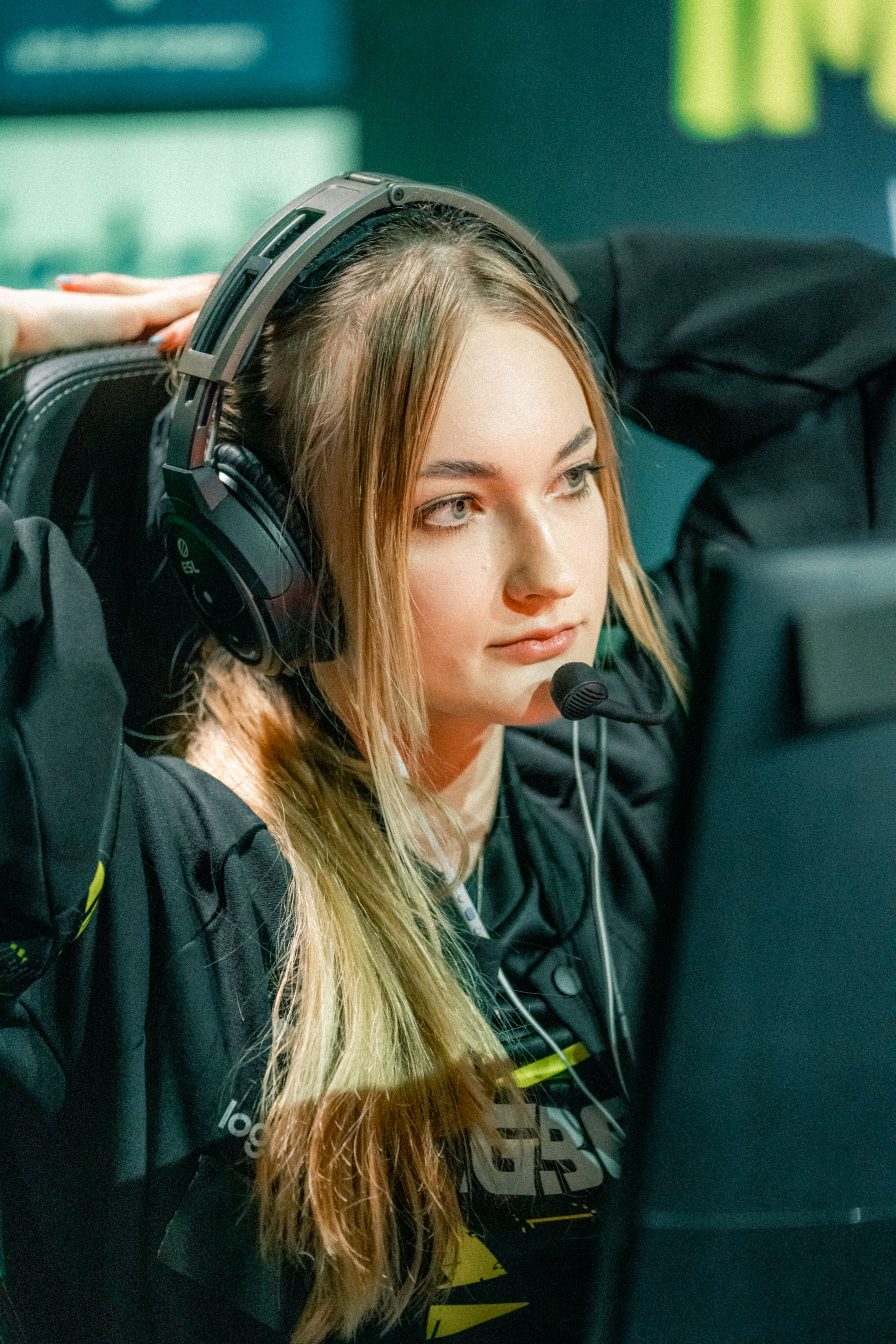 Young female gamer with headset intensely focused during an esports competition.