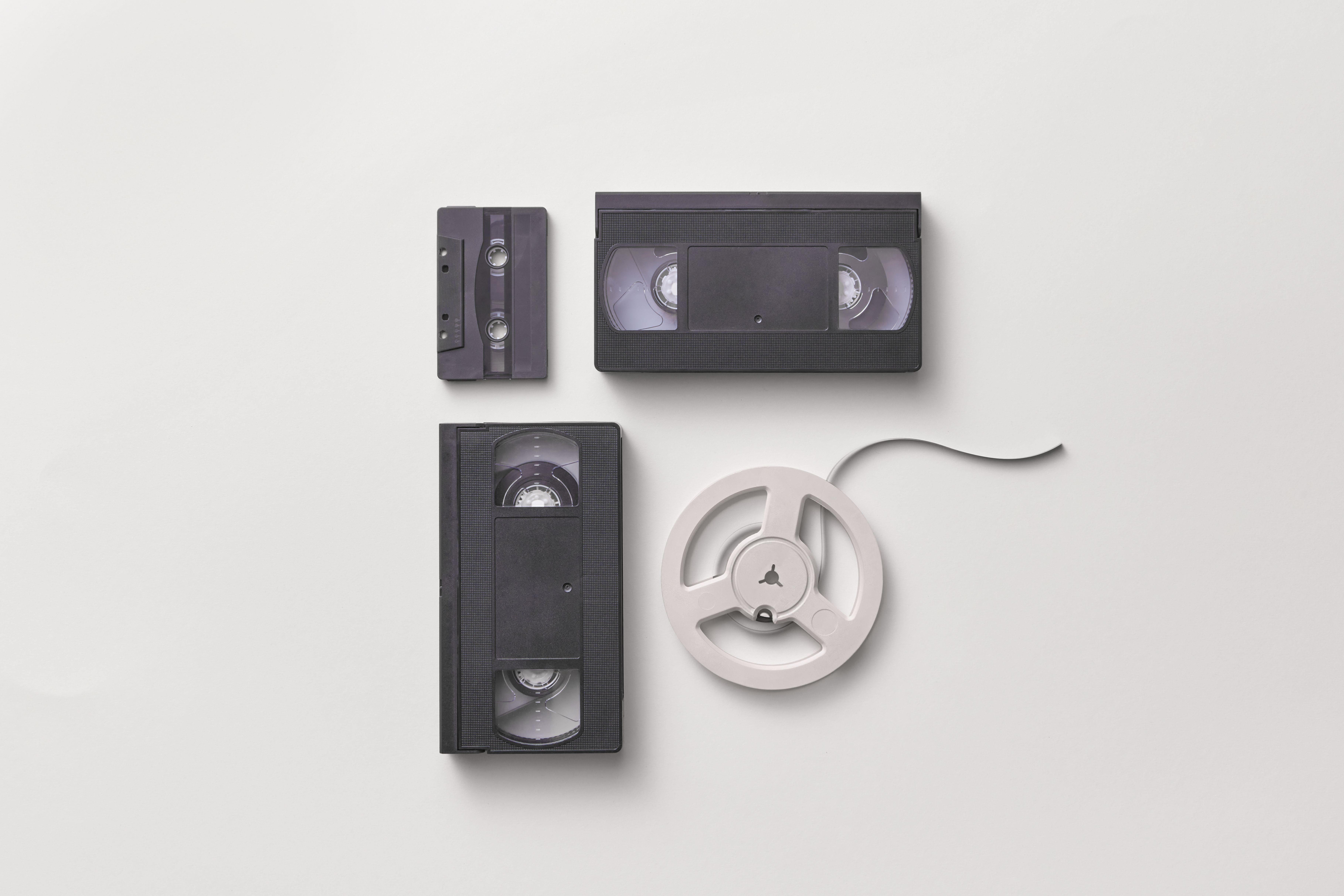 Collection of vintage audio and video tapes including VHS and cassette on a white background.
